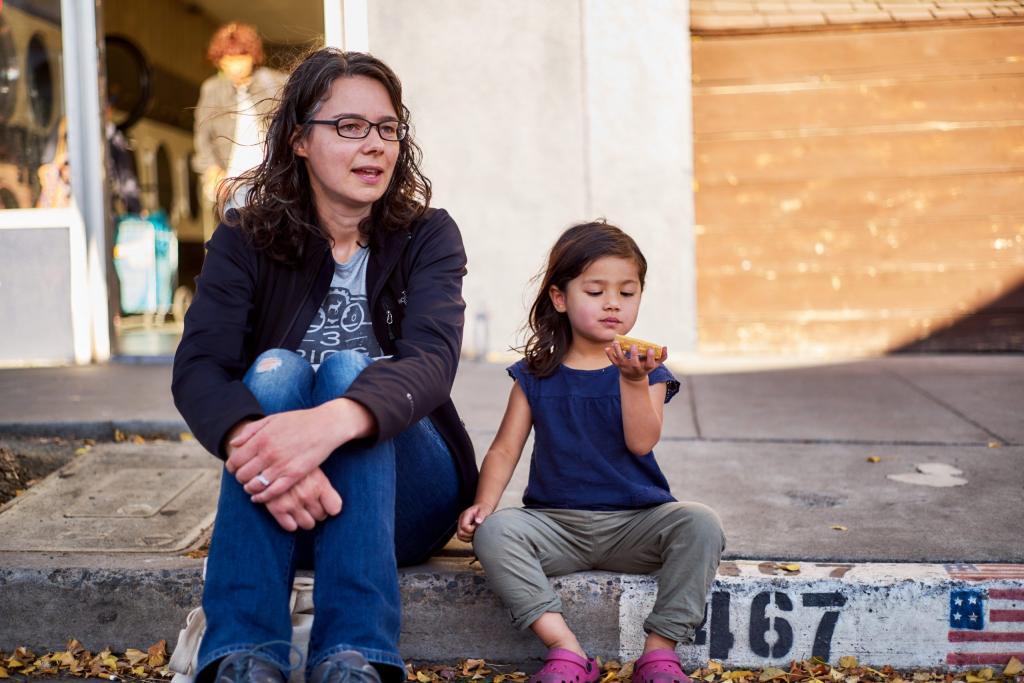 Jen and her daughter enjoying a snack sitting on the curb.