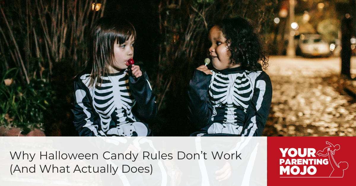 Two children in skeleton costumes stand together at night, one eating candy while the other looks on and smiles.
