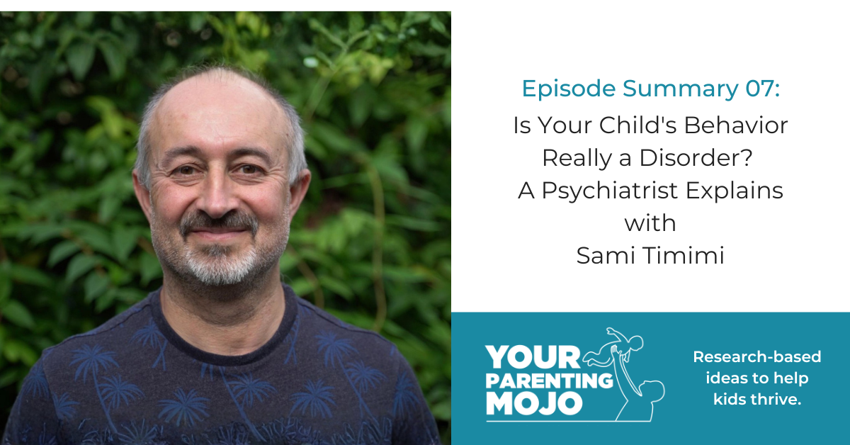 a smiling middle-aged man with a beard standing outdoors in front of green foliage