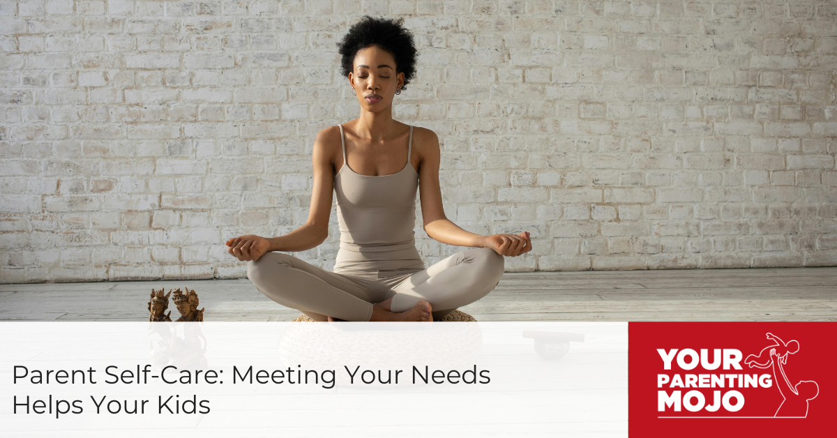 A Black woman sits in a meditation pose on a woven cushion, eyes closed, hands resting on her knees, wearing a light beige outfit. A white brick wall is behind her.