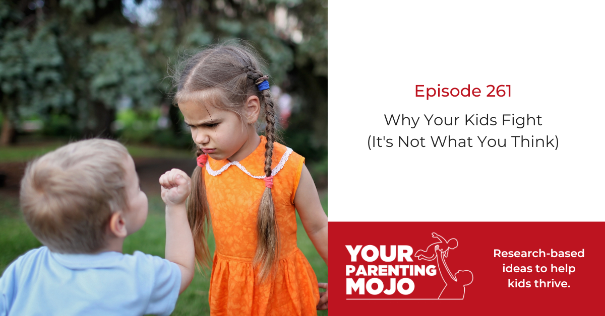 A young girl in an orange dress raises her fist toward a smaller child outdoors.